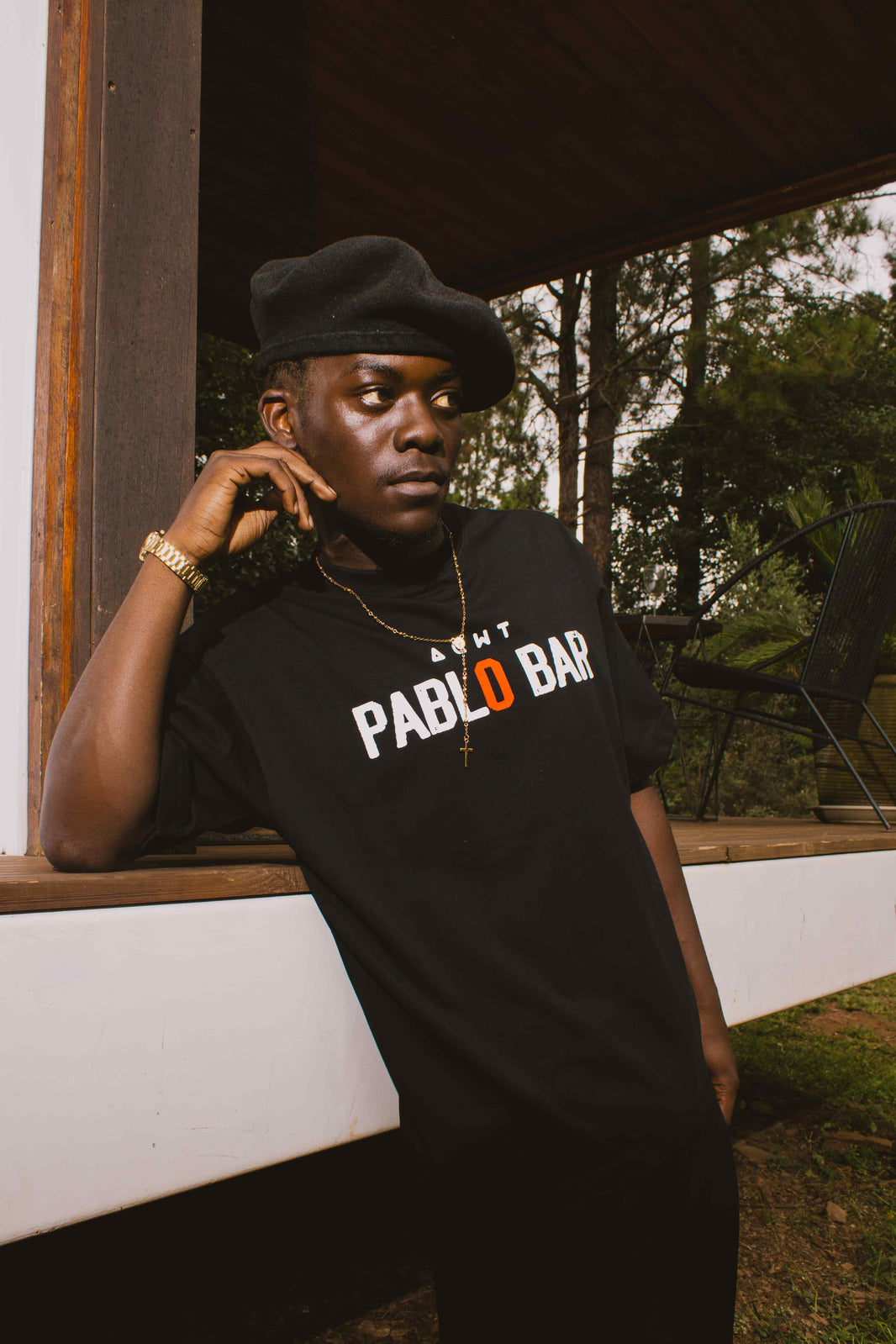 Men’s streetwear outfits with black graphic tee, beret and layered accessories styled in a relaxed outdoor scene.