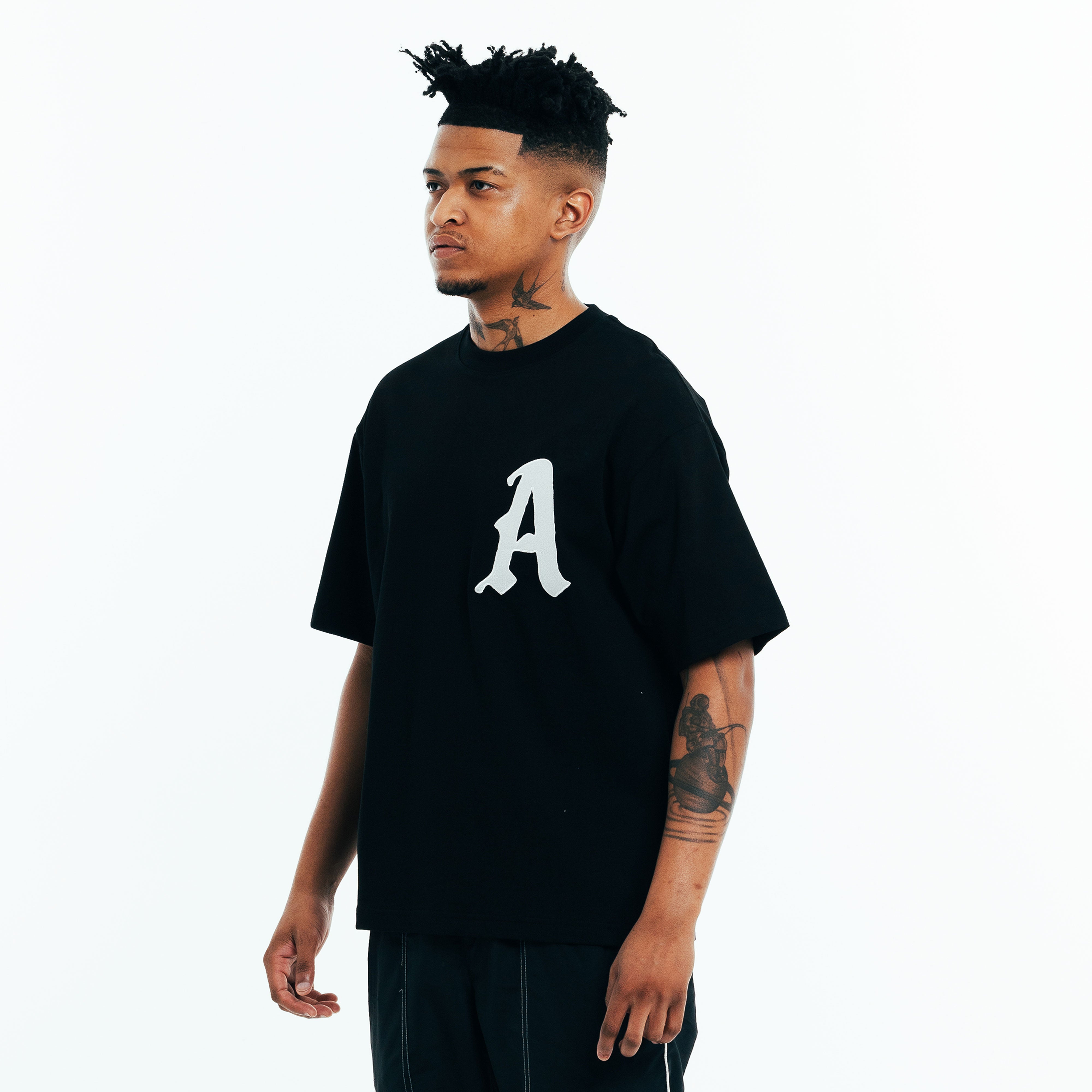 Model wearing black t-shirt with front logo, cotton t-shirt fit